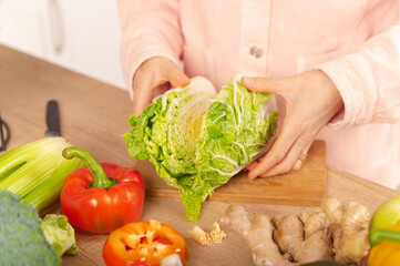 Young female hands has just cut a green Chinese cabbage into two pieces.