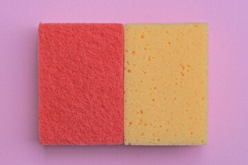 two yellow and red foam sponges lie on a pink table