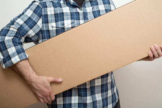 Man hand holding a long size cardboard box of new furniture set. Delivering concept.