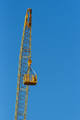 Naklejka premium Construction crane with basket against the blue sky.