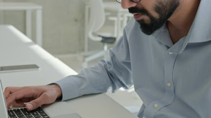 Thoughtful Arabian Indian man muslim male businessman entrepreneur lawyer professional executive manager working laptop check information count budget read business contract legal documents paperwork