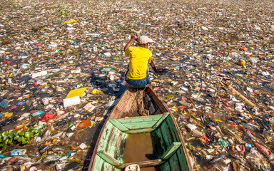 People collect trash that can be recycled and traded from the sea of garbage in the Citarum River,...