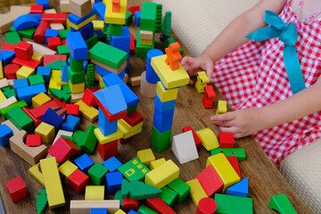 Naklejka premium smart little child, girl 3 years old playing with educational toy, wooden geometric figures, blocks, kindergarten games, concept of childhood, earlier child development, creativity, early training