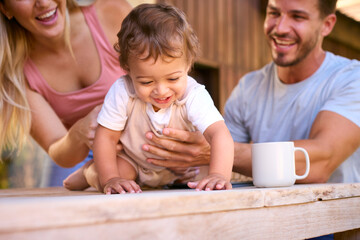 Family Shot As Parents Play With Young Son At Home Whilst Using Digital Tablet