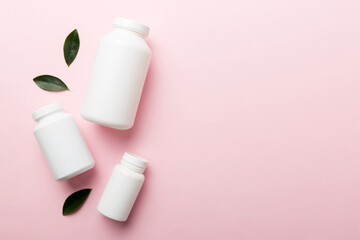 supplement pills with medicine bottle health care and medical top view. Vitamin tablets. Top view mockup bottle for pills and vitamins with green leaves, natural organic bio supplement, copy space