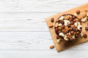 Assortment of nuts in wooden bowl on colored table. Cashew, hazelnuts, walnuts, almonds. Mix of nuts Top view with copy space