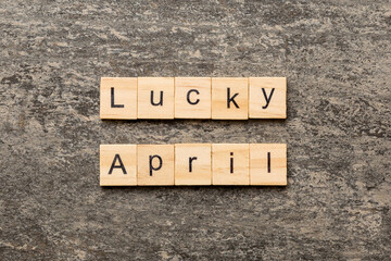 Fototapeta premium lucky april word written on wood block. Happy april text on table, concept
