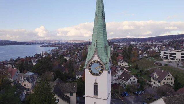 Aerial panoramic drone view of Uetikon and local church, Reformierte Kirchgemeinde Zollikon, with Zurich in the background, Switzerland