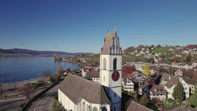 Aerial panoramic drone view of the Horgen to Meilen ferry crossing Lake Zurich, and local church, Reformierte Kirche Meilen, Meilen, Switzerland