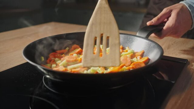 Close-up. The process of frying chopped vegetables in a frying pan at home kitchen. Cookery concept