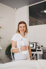 Portrait of happy dermatologist, skin therapist, beautician and skincare professional in workplace. Smiling beautiful young woman in white uniform