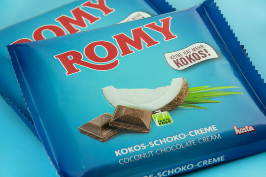 Hosta Romy Kokos Creme Schokolade Vollmilch mit Verpackung auf blauem Hintergrund
