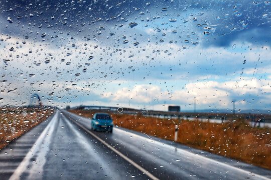 Coche y carretera en día de tormenta. Concepto de conducción segura. Imagen abstracta de coche y carretera A través de la ventana mojada.