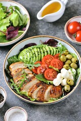 Fototapeta na wymiar Healthy salad with grilled chicken breast, mozzarella, avocado, olives and cherry tomatoes