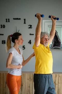 Professional physiotherapist working with a senior man teaching him how to workout properly