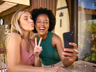Smiling Female Friends Outdoors At Home Posing For Selfie On Mobile Phone Together
