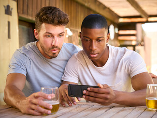 Two Male Friends Outdoors At Home Watching Sports Action On Mobile Phone