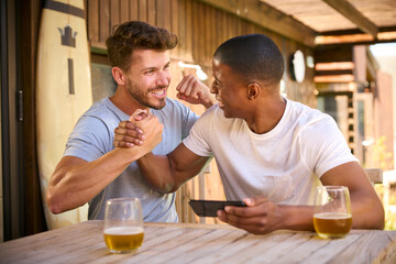 Fototapeta na wymiar Two Male Friends Outdoors At Home Watching Sports On Mobile Phone Celebrating Team Win