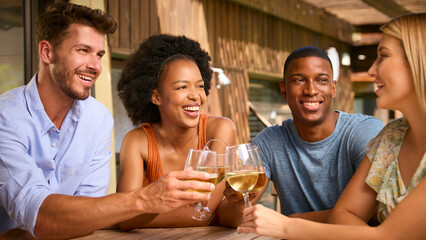Group Of Smiling Multi-Cultural Friends Outdoors At Home Drinking Wine Together