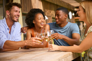 Group Of Smiling Multi-Cultural Friends Outdoors At Home Drinking Wine Together