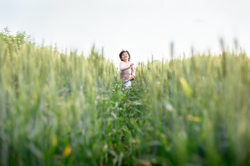 smiling girl with short hair in pink top run happily in wheat field