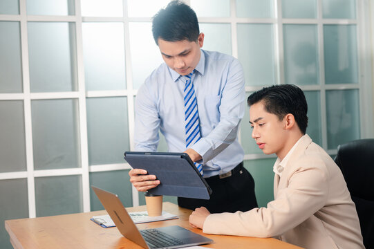 Two business people during work meeting in modern office explaining statistics data to each other,Making reports, analitycs, routine processing tasks. Concept of business, finance, professional