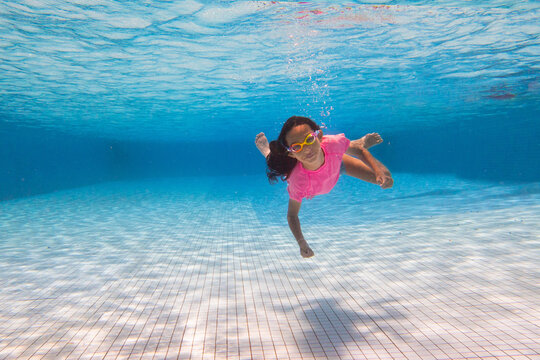 Child in swimming pool on ring toy. Kids swim.