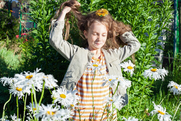 Caucasian girl with dark hair in summer near daisies