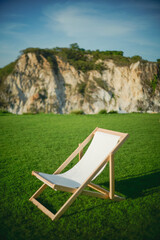 Modern beach chairs are on a field with mountain background.