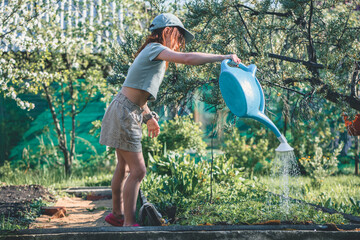 girl watering blooming tree with watering pot in the garden.