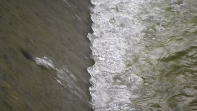 The water flows through the concrete weir with the gentle sound of water flowing and the beautiful singing of birds. Create a peaceful atmosphere filled with the beauty of nature.close up. slow motion