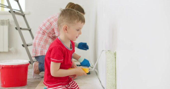 Mother and her son painting wall with paint roller and brush at home