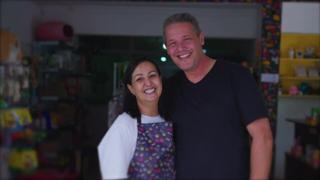 Authentic joyful couple owners of Small Local Business posing for camera smiling. Brazilian Entrepreneurs of Pet Shop in storefront