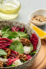 mixing delicious superfood salad with beet fresh baby spinach, cheese, nuts. Clean eating, dieting, vegan food concept. Food recipe background. Close up