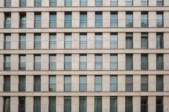 Outdoor exterior front view of modern facade with typical rectangular windows with reflection glass and randomly opening curtains.