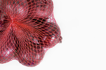 Onion Red. In a shopping plastic mesh on white. Close-up. copy space