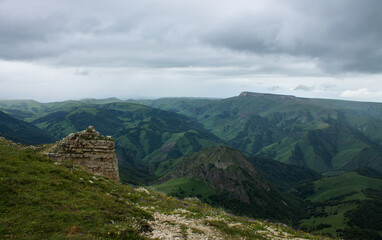 Fantastic dramatic landscape - panoramic view of the hilly valley blurred in the morning fog from the Bermamyt plateau in Karachay-Cherkessia on a cloudy summer day