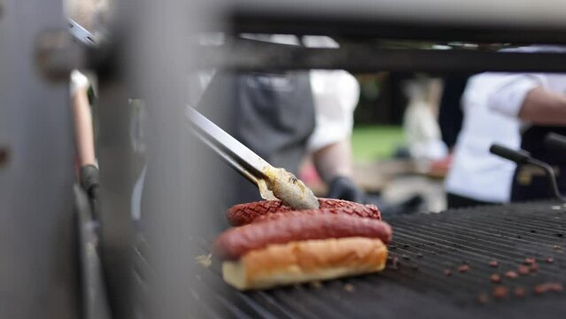 cook cooking hotdog. Fried delicious sausages on a barbecue grill over a fire.