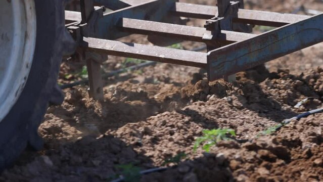 close up of soil aeration with tractor. Blades of a rototiller working the land, agriculture, slow motion close up