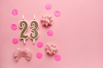 Number 23 on pastel pink background with festive decor. Happy birthday candles. The concept of celebrating a birthday, anniversary, important date, holiday. Copy space. Banner