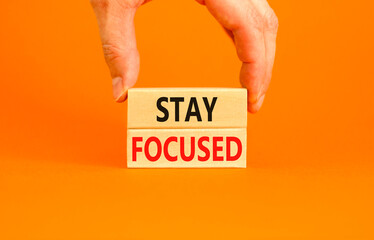 Stay focused symbol. Concept words Stay focused on wooden blocks on a beautiful orange background....
