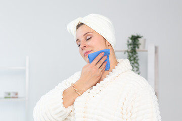 Excited joyful young woman wrapped head in towel holding dry brush shower sponge and doing spa procedure