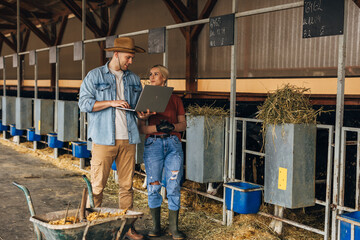 Man and woman standing in a stall and using a laptop.