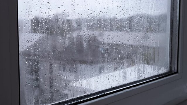 Woman Touches a Wet Misted Window with Hand. Fingers slide on wet glass. Drops of the condensate flow down. Isolation is at home. Gloomy rainy day. Hope, separation, despair, longing, loneliness.