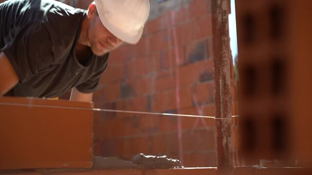 Young boy working on a construction site with no helmet or safety measures. Puts cement and a brick. Youth entrepreneurship concept