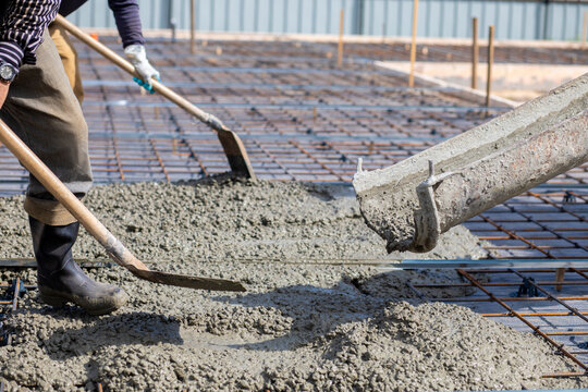 A worker spreads concrete with shovels over.