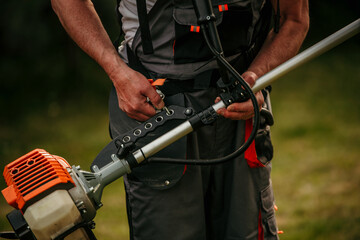 Senior worker preparing to use a lawn trimmer cutting grass in the natural background. Housework...