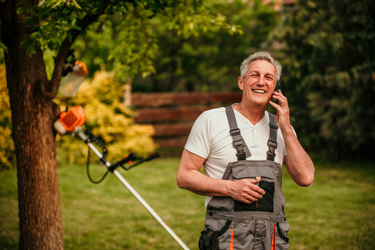 senior man talking on the phone while working in his backyard. - Powered by Adobe