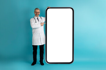 Handsome middle aged doctor showing big smartphone with white screen