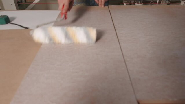 Close up of process of priming wooden board surface at the factory. Industrial background, concept of carpentry.